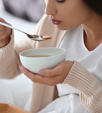 Woman eating soup after tooth extraction 