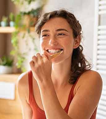 Woman in red shirt brushing her teeth