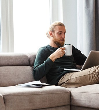Young man sitting and working on couch