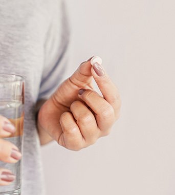 Woman taking pill after dental implant surgery