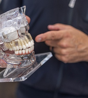 Oral surgeon using model to talk about dental implants