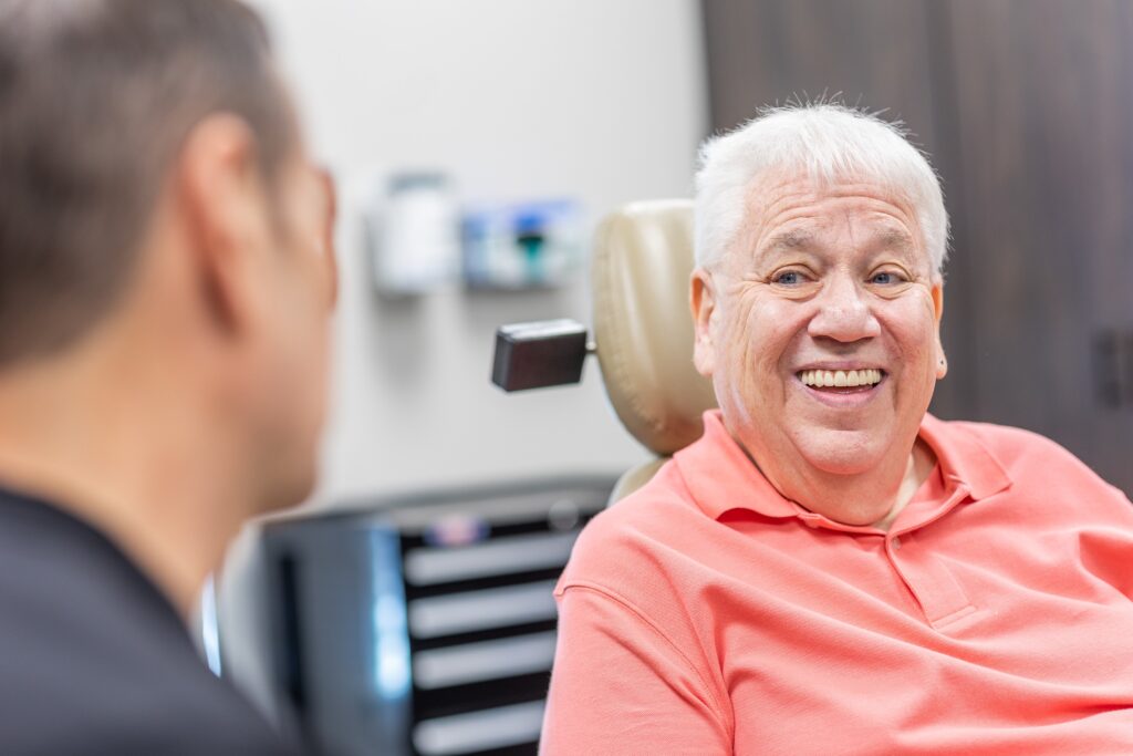 older man smiling at dental implant consultation 