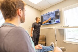 Dr. Josh Matonak pointing to an X-ray on screen with a patient during consultation