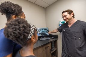 Oral surgeon Dr. Bryce Hallinan showing a patient and her mother her panoramic X-rays on a computer screen.
